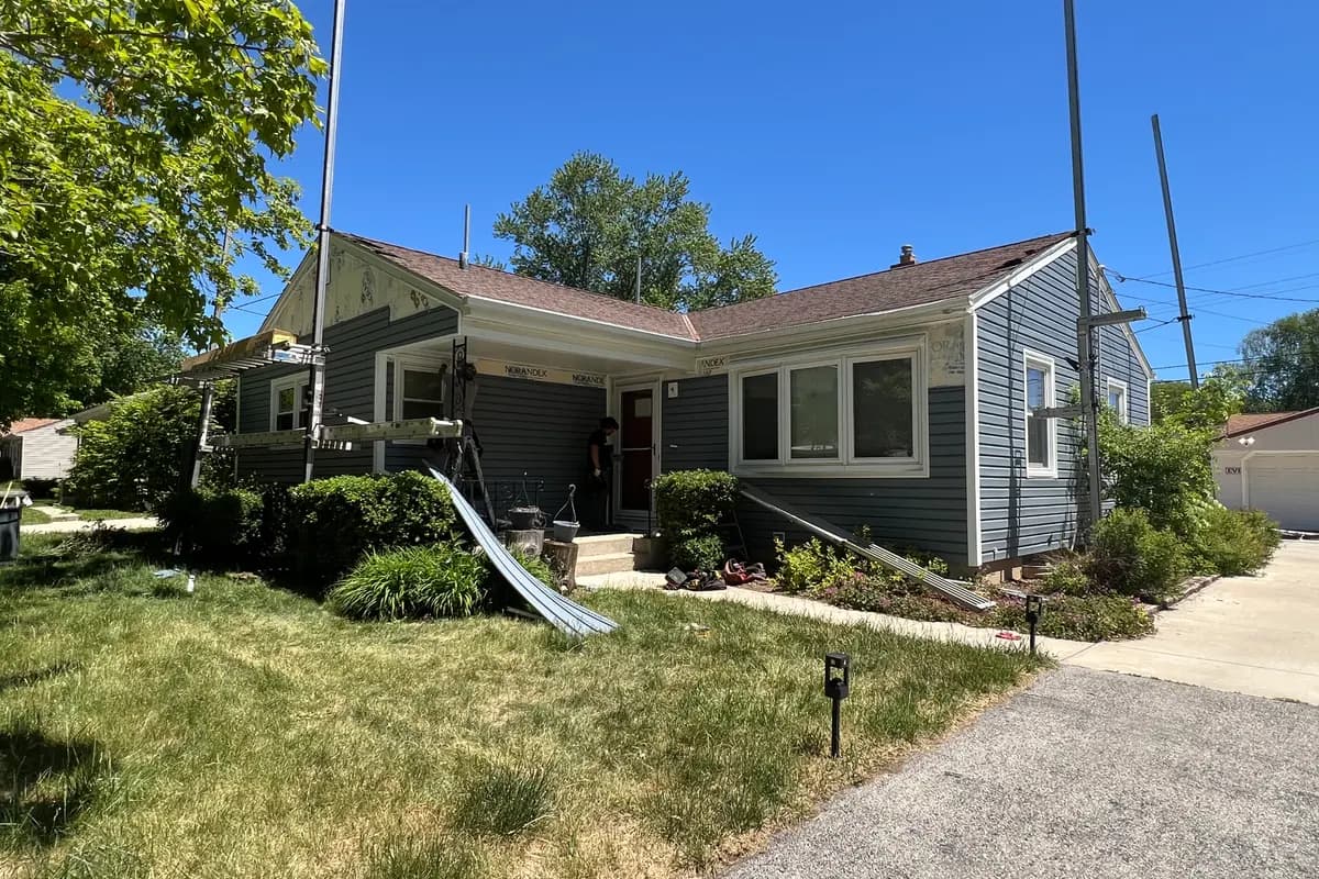 Apexium Roofing ladder set against a tree-shaded Elm Grove, WI home