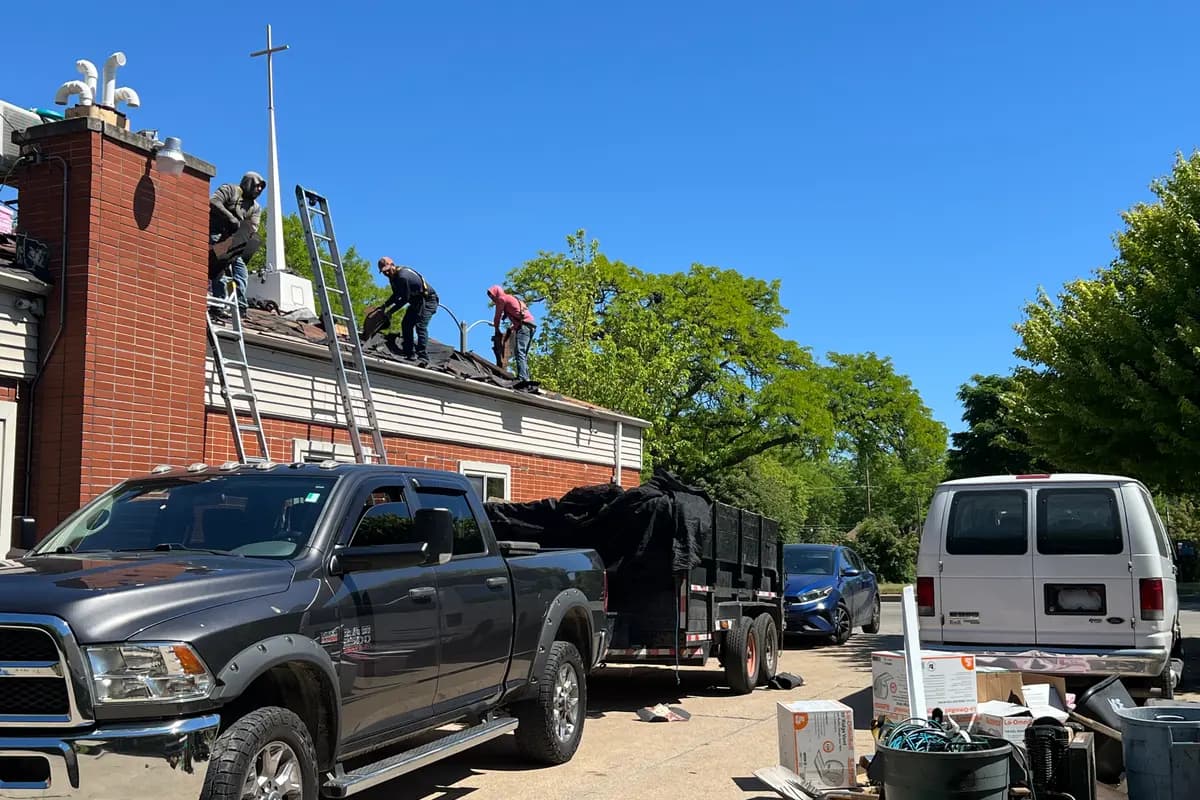 Apexium Roofing crew and dump trailer during a brick building roof replacement in Milwaukee, WI