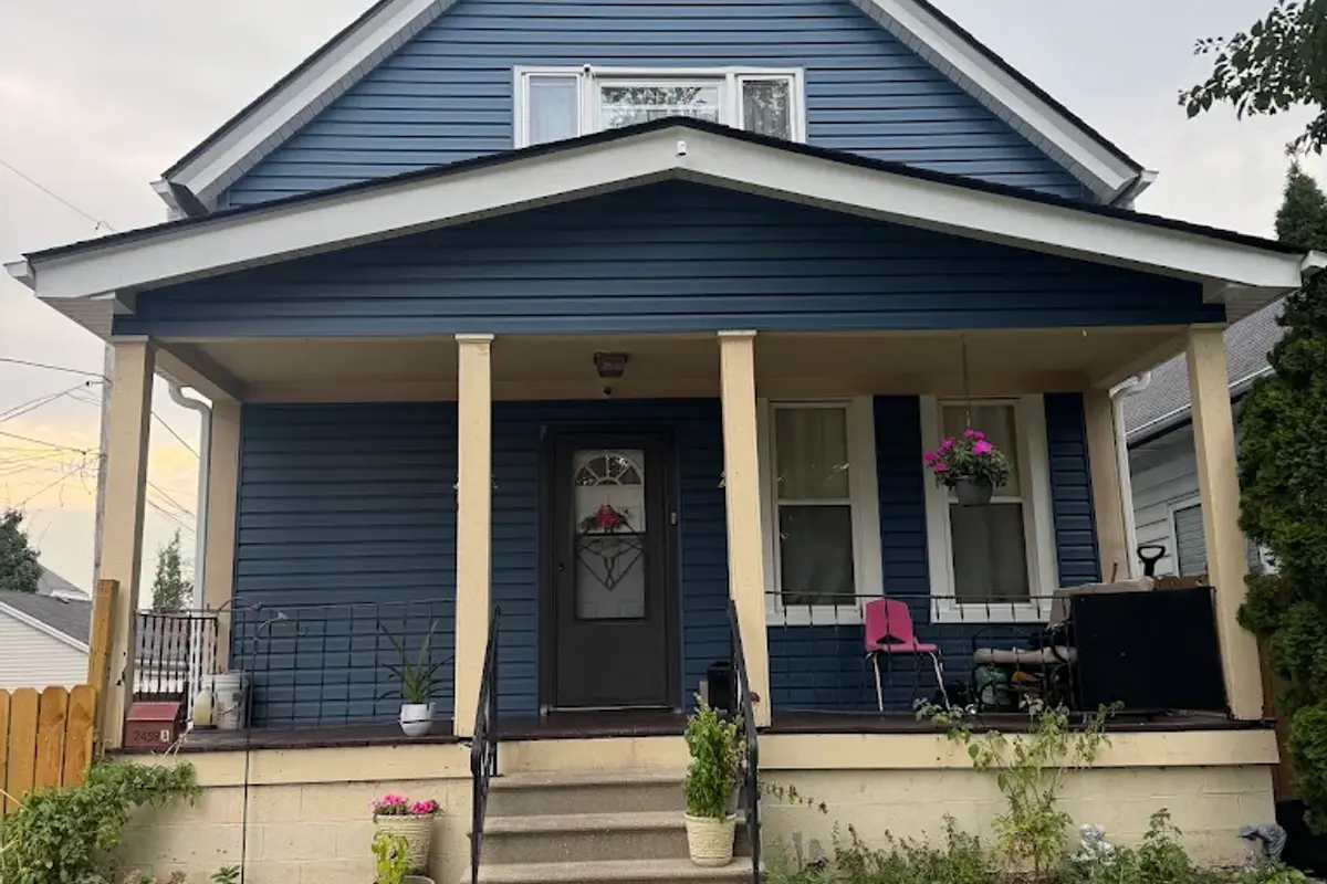 Completed roof replacement on a blue two-story home with a full front porch in Shorewood, WI